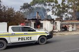 A police four-wheel drive ute outside a burnt-out petrol station