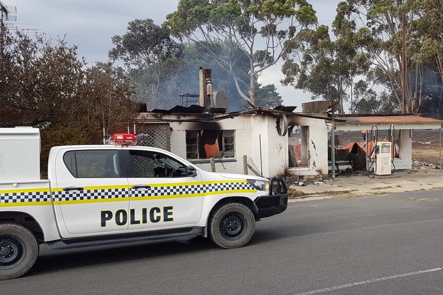 A police four-wheel drive ute outside a burnt-out petrol station