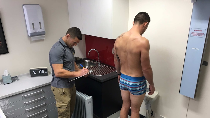 Athlete is weighed on digital scales by doctor as part of water loading research