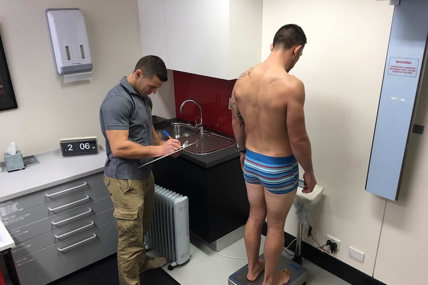 Athlete is weighed on digital scales by doctor as part of water loading research