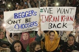 Women in a crowd hold posters reading 'Beggars can't be choosers' and 'We want Imran Khan back'