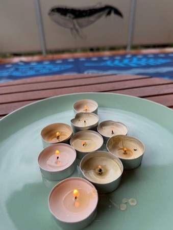 Nove pequenas velas acesas num prato azul claro.