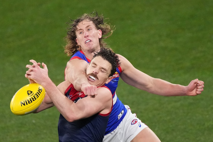 Two AFL player fighting for the ball during a match 