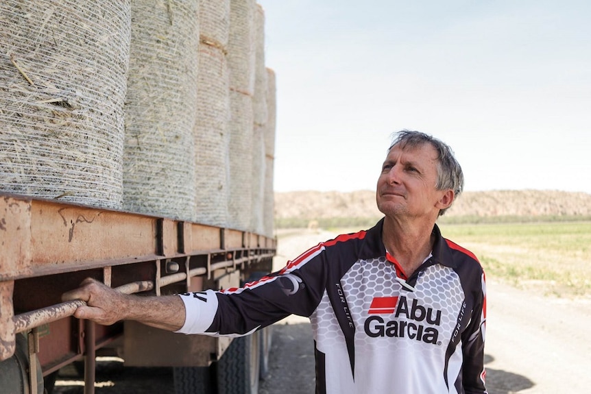 Rob Boshammerlooking at hay bales on the back of a semi trailer.