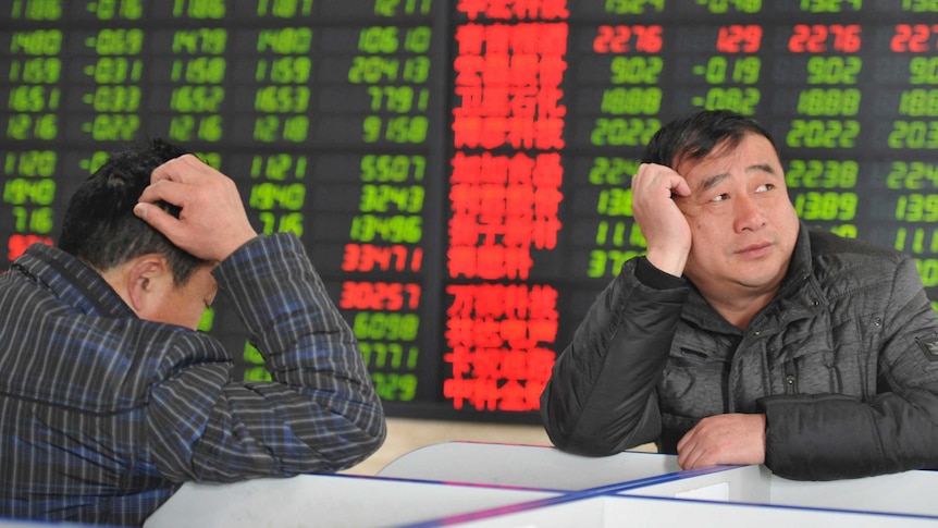 Investors react in front of an electronic board showing stock information at a brokerage house in Fuyang, Anhui province,