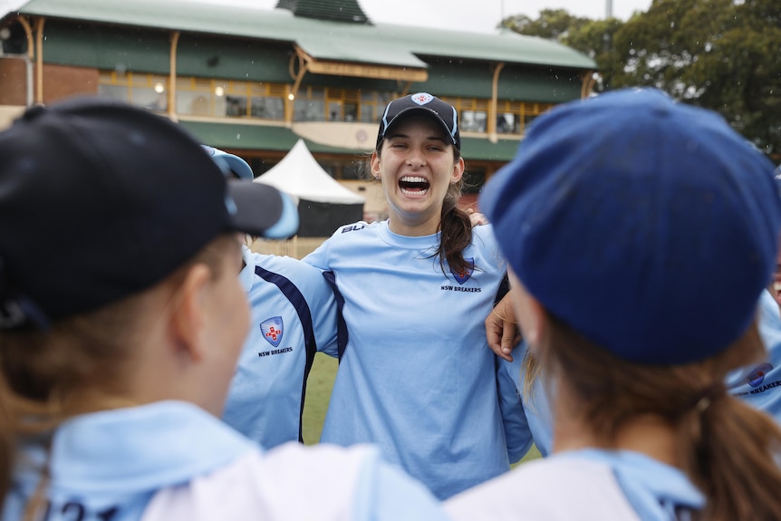 Stella Campbell looks up and smiles while in a huddle with her teammates.