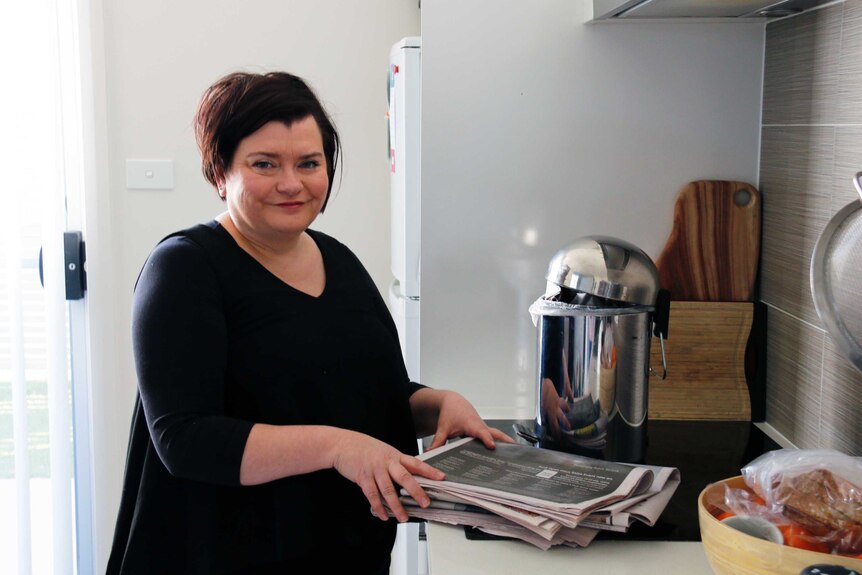 Susie of north Canberra in her kitchen with her garbage, which she wraps in old newspaper.
