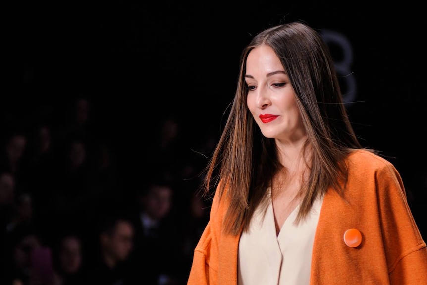 Model and activist Angel Dixon on the catwalk wearing an orange coat.