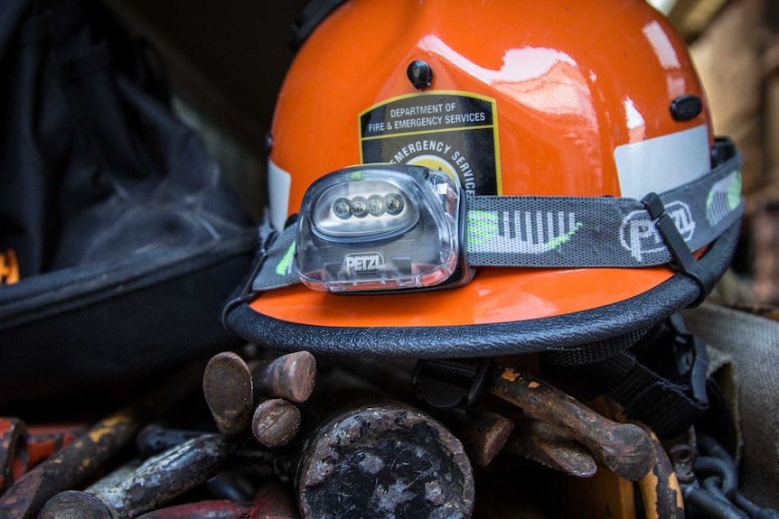 An SES hard hat rests on some tools.