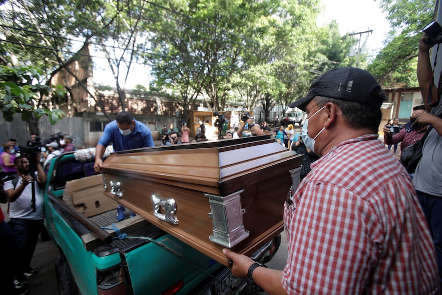 People load a casket with the body into a truck outside a morgue in Tegucigalpa, Honduras.
