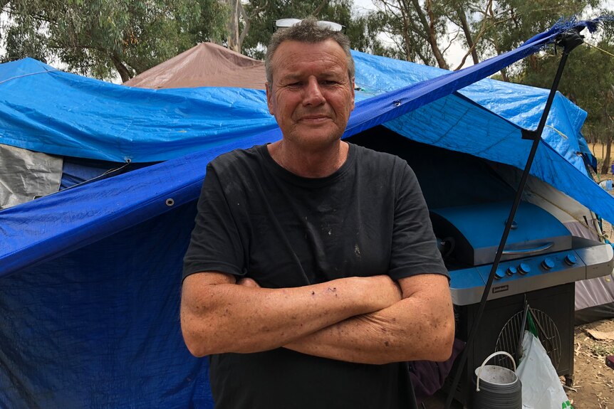 A man stands with his arms crossed looking at the camera