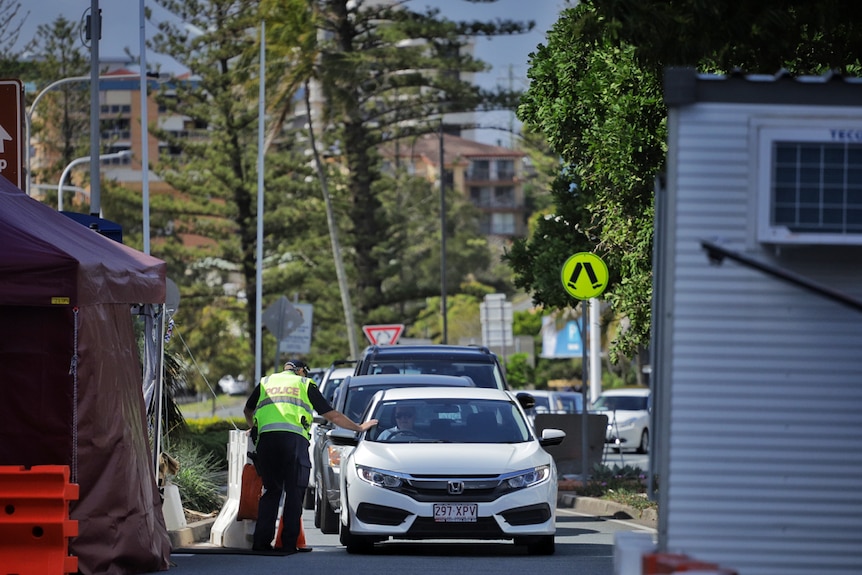 An officer checks a motorist at the Queensland border checkpoint at Griffith Street, Coolangatta.