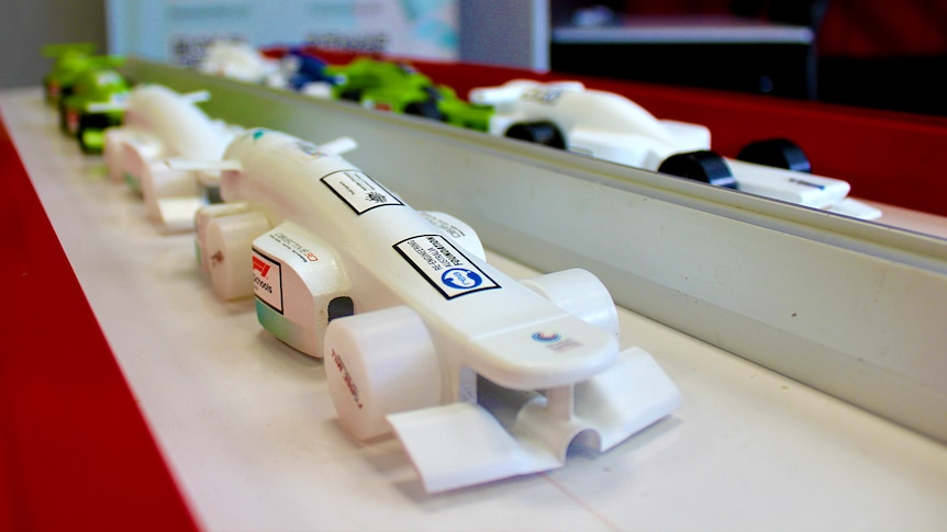 Eight compressed gas cylinder powered race car models lined up for display on a track.