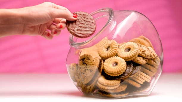 hand taking cookie from cookie jar