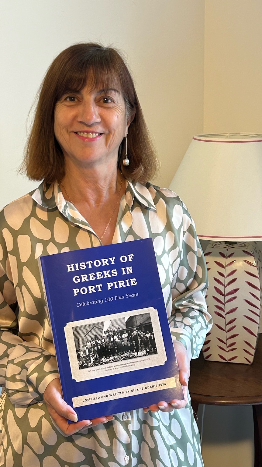 A woman stands holding a bright blue history book. 