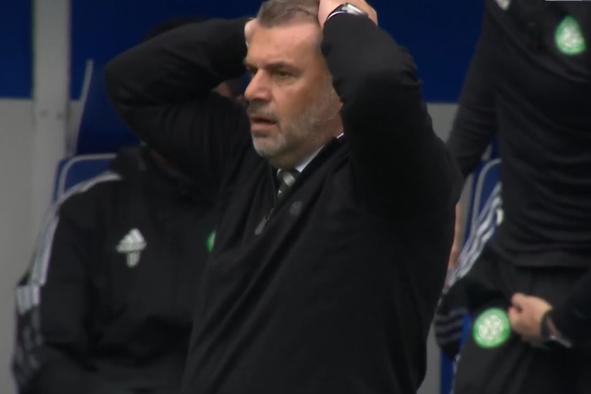 Ange Postecoglou puts both hands on his head and stands with his mouth agape
