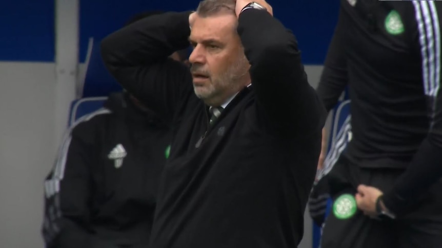 Ange Postecoglou puts both hands on his head and stands with his mouth agape