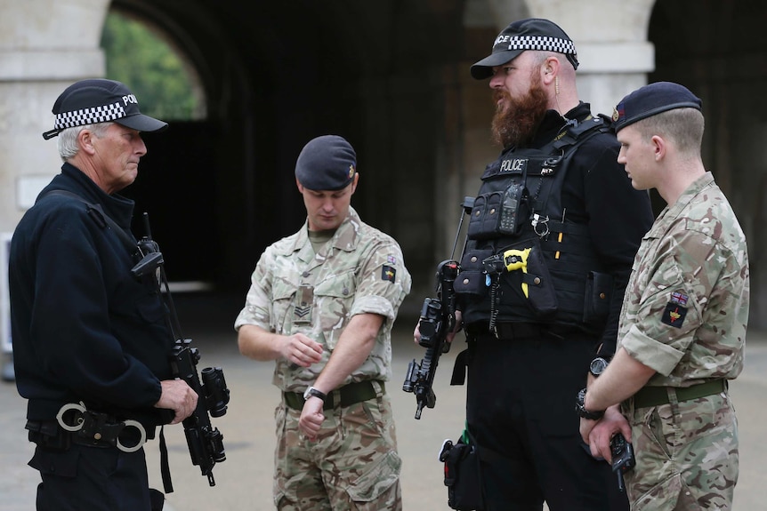 Two police officers and two soldiers stand in a group and talk.