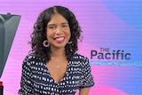 Woman leaning on camera in TV studio with backdrop saying The Pacific.