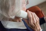 Elderly woman holds a phone up to her ear