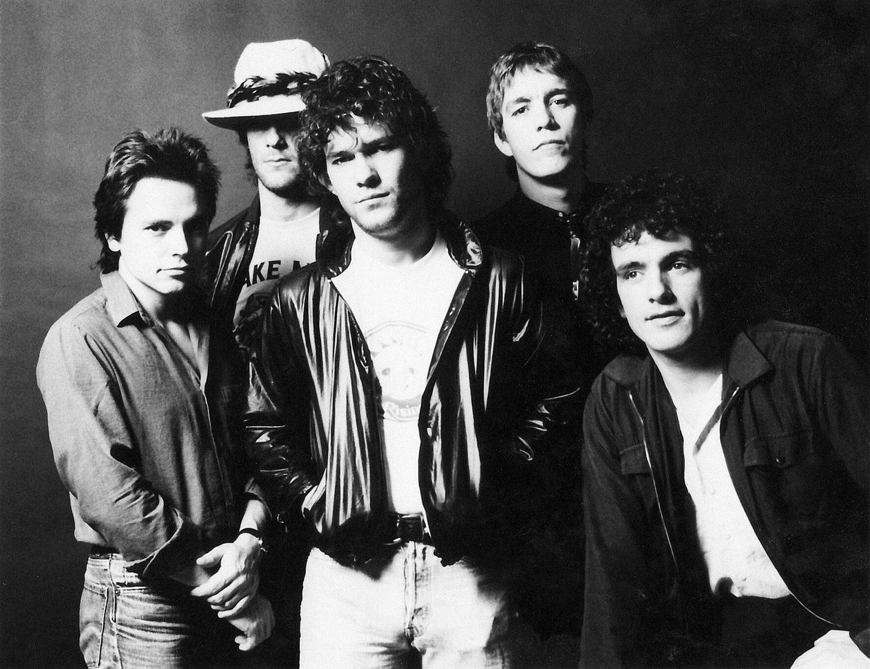Cold Chisel band pictured in black and white. Five men look at the camera. Jimmy Barnes, centre, wears a black leather jacket.