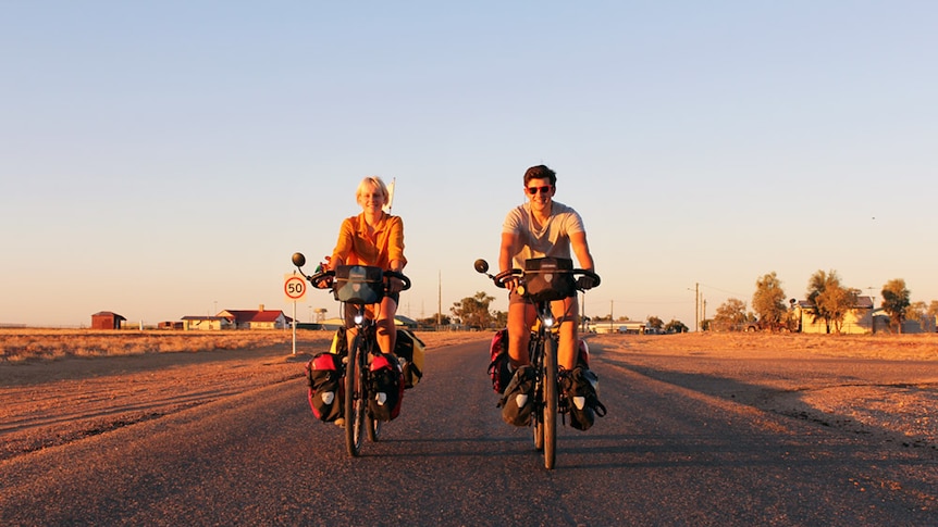 Bobbie Bayley and Owen Kelly riding towards the camera in Birdsville's sunset