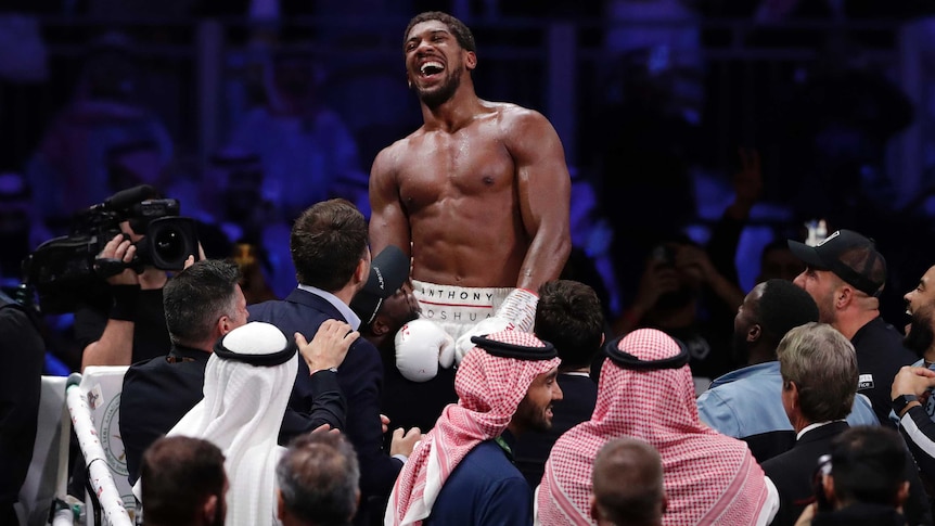 A boxer laughs in the ring after his win in a world heavyweight title fight.
