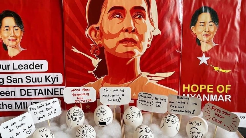 A display of eggs with writings and small signs sits in front a picture of an elderly Asian woman.