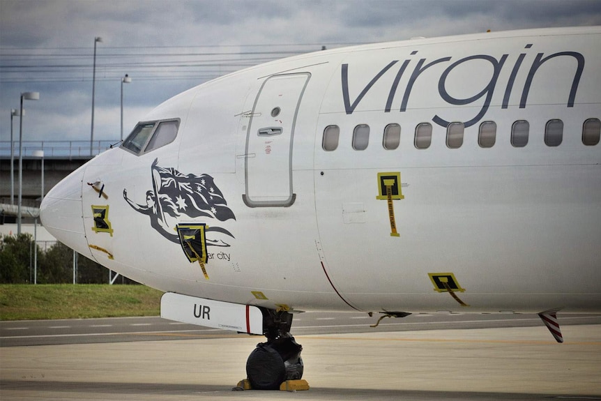 The nose of a Virgin passenger plane parked on airport tarmac.