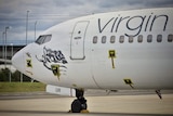 The nose of a Virgin passenger plane parked on an airport tarmac