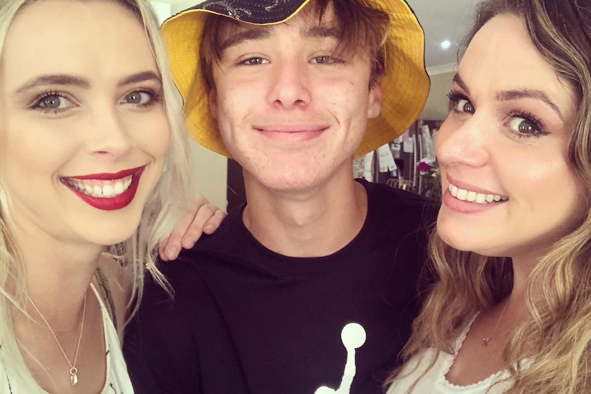 Young woman, teenage boy and adult woman side by side smiling