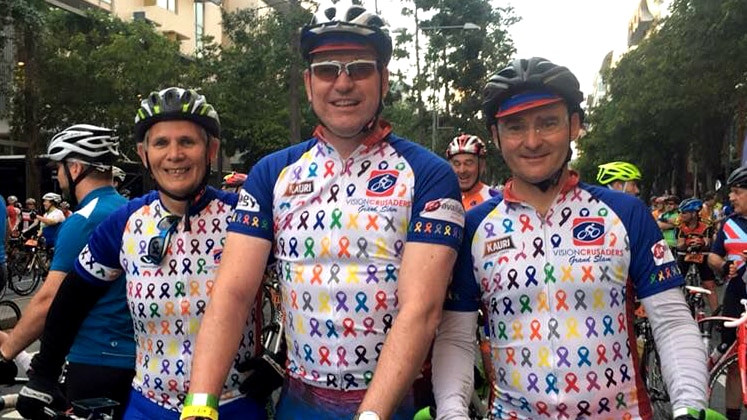 Three male cyclists on their bikes, smiling.