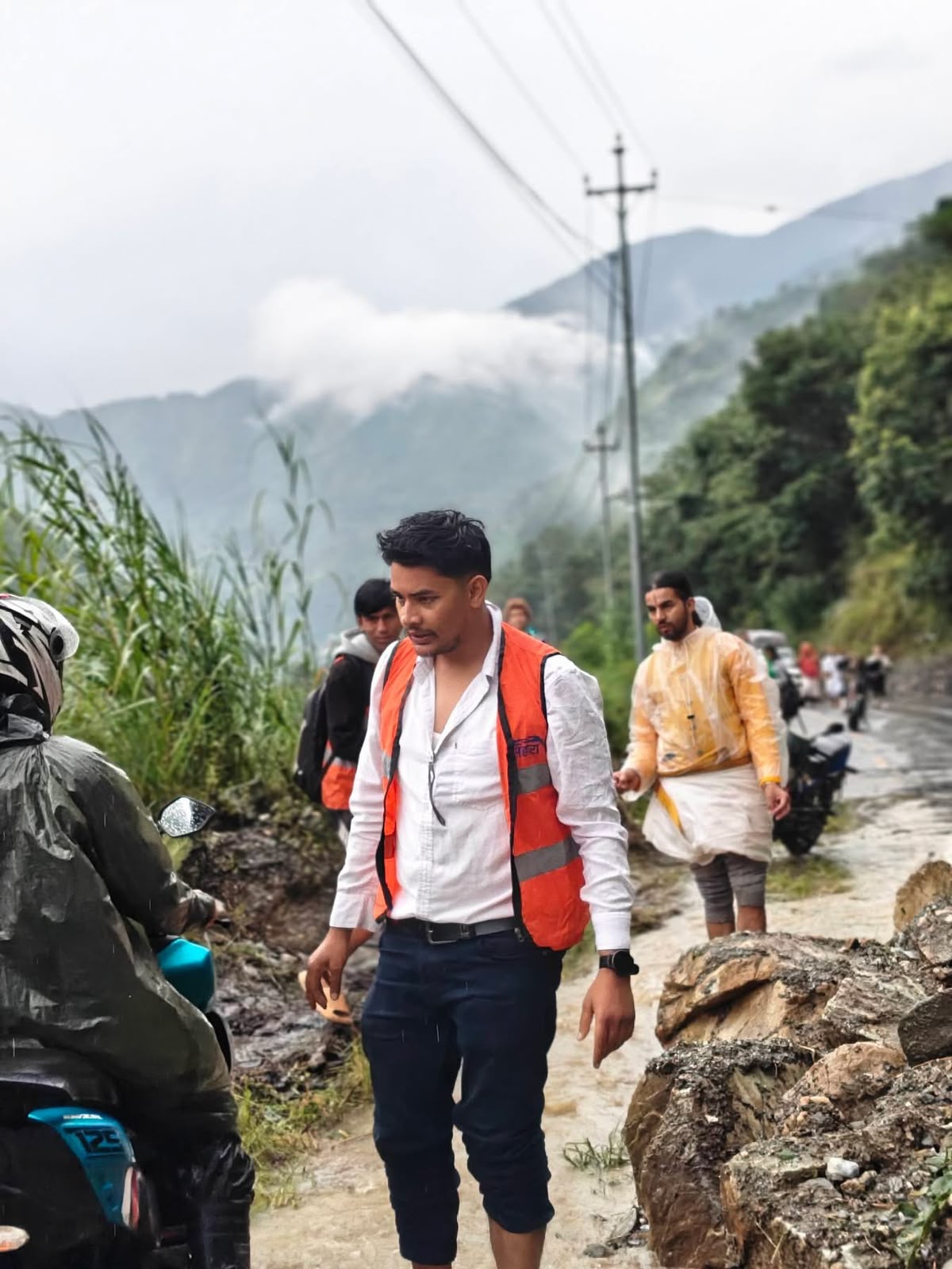 A man in high vis stands on a road, helping people.