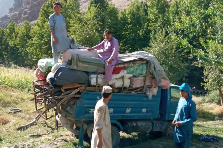 Four men with a truck carrying mattresses and other personal belongings. 