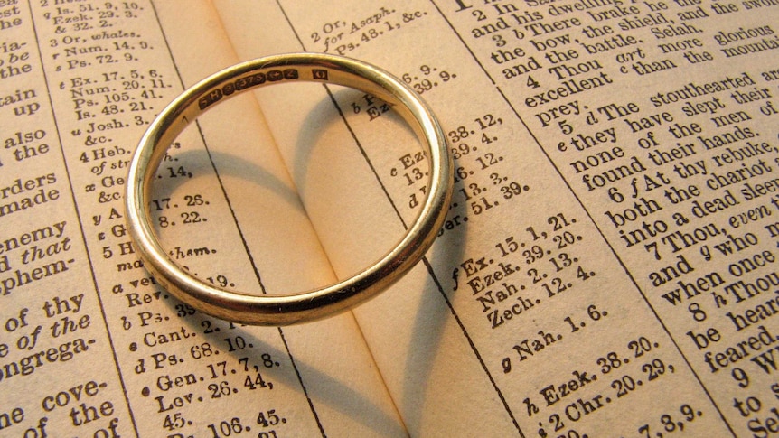 A wedding ring sits on a bible.