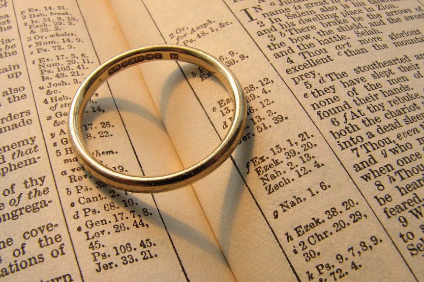 A wedding ring sits on a bible.