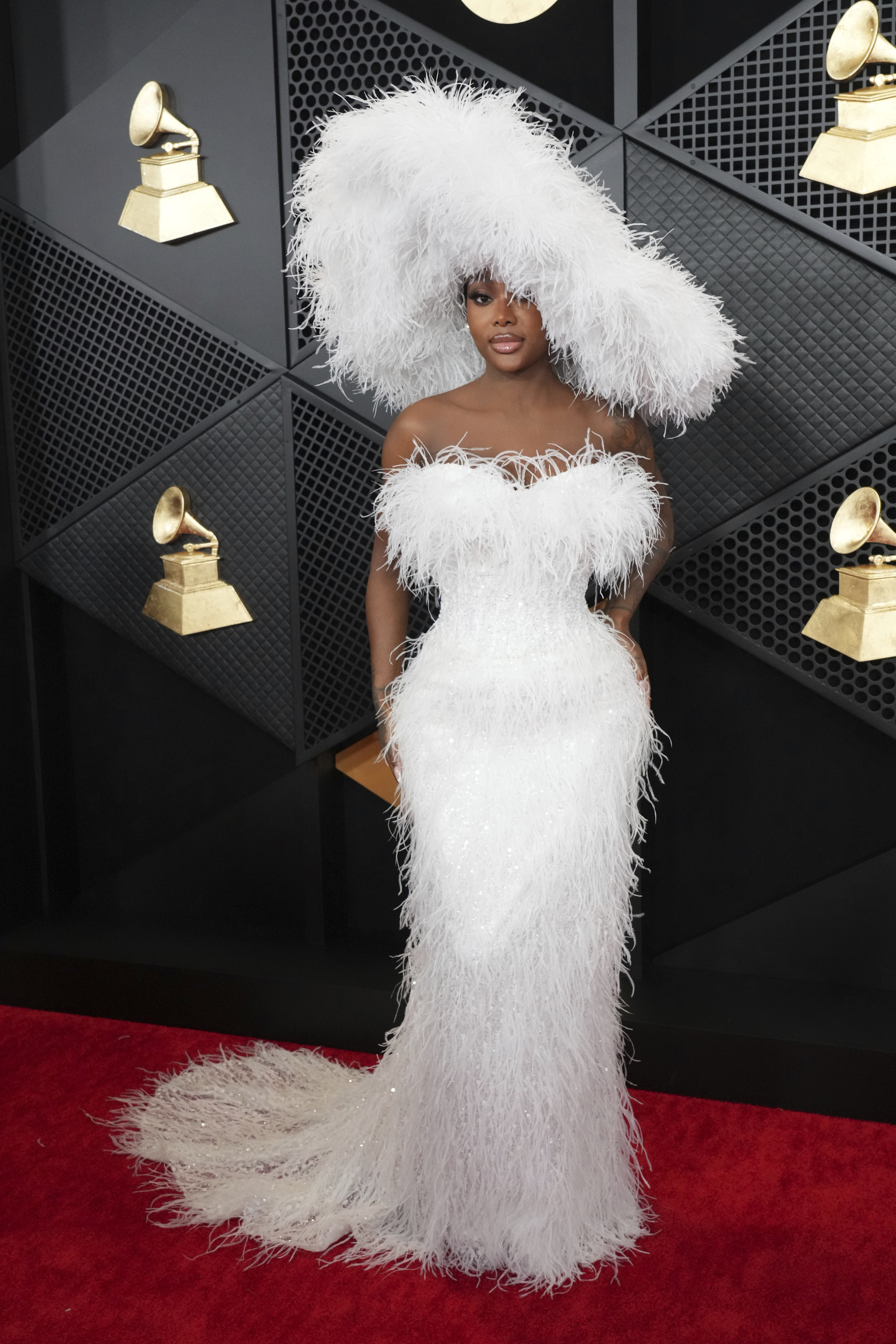Summer Walker wearing a tight, white strapless gown with fluffy feathery fabric and a massive matching fluffy hat