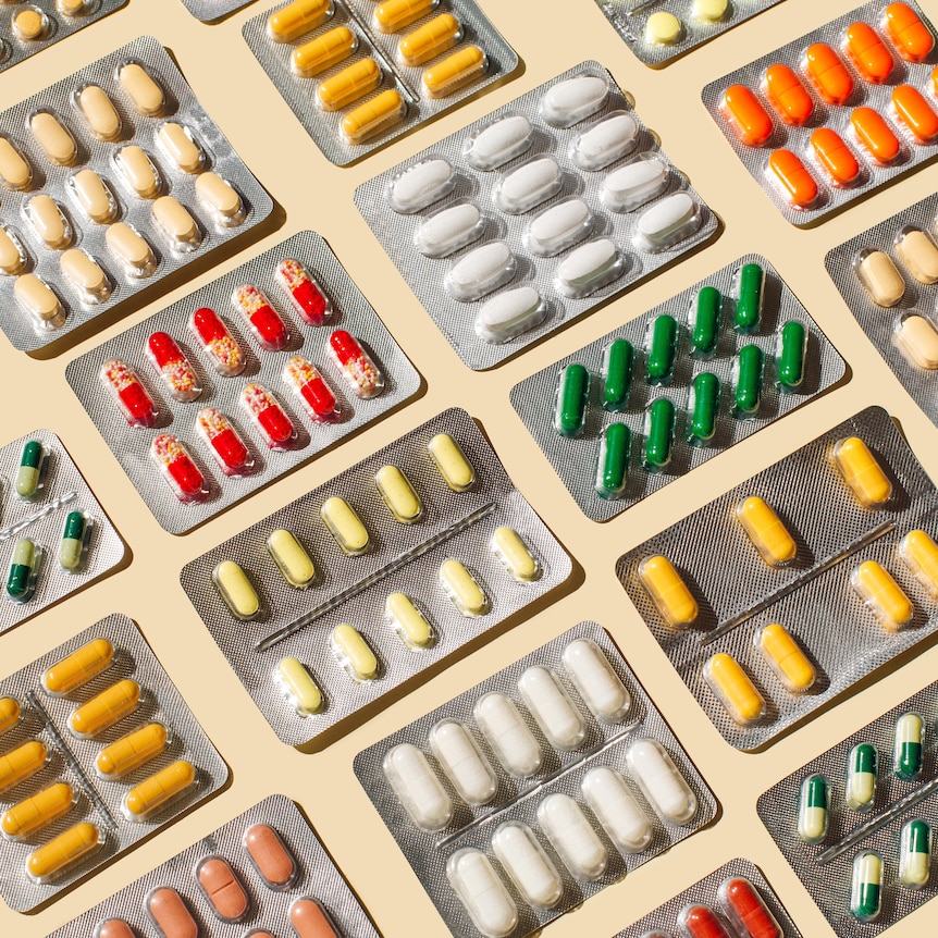 Blisters with colorful pills and capsules on beige background