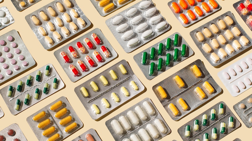 Blisters with colorful pills and capsules on beige background