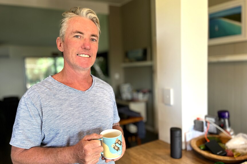 a man holding a mug in the kitchen