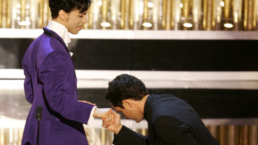 Jorge Drexler bends down as if he is kissing Prince's hand after he - Drexler - won his Academy Award for best original song.