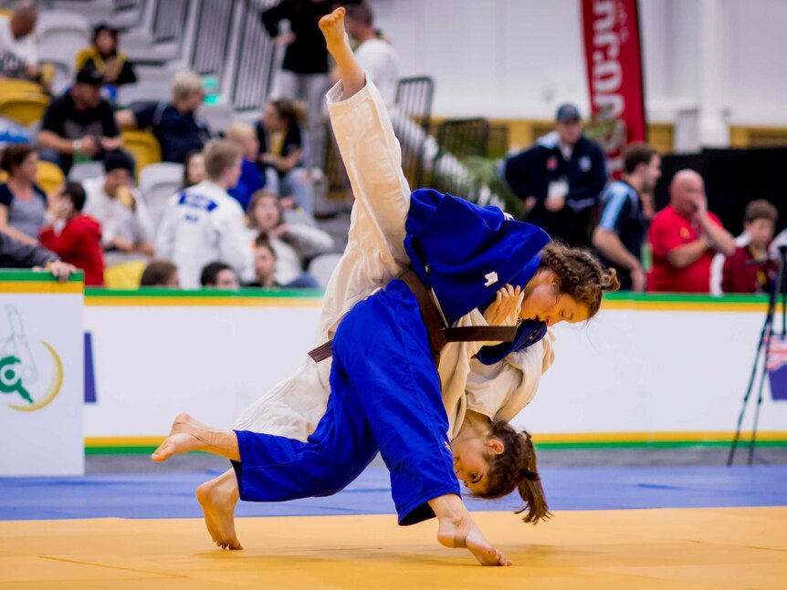Sophie Robins (in blue) throws a competitor, whose legs fly up into the air.