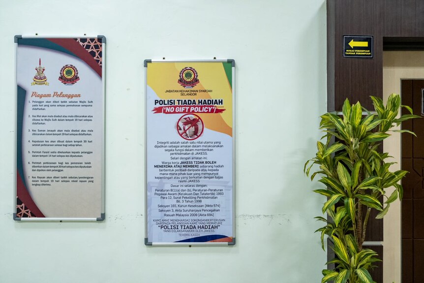 Signs inside a sharia high court in Malaysia, written in Malaysian, say "no gift policy".