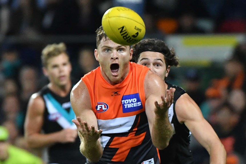 Heath Shaw opens his mouth and eyes wide as he prepares to catch a yellow AFL ball in his outstretched arms.