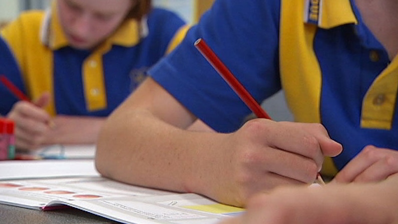 Generic TV still of 2 anonymous students writing at school desk at unidentified Qld primary school.