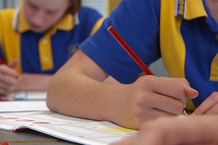 Two children write at desks at a school.