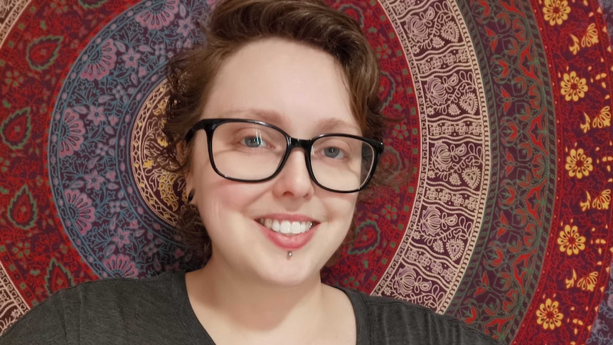 A woman with short dark hair and glasses smiles. For story on women finding exercise that suits them.