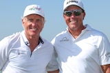 Greg Norman and Phil Mickelson smile together for a forward with the beach behind them
