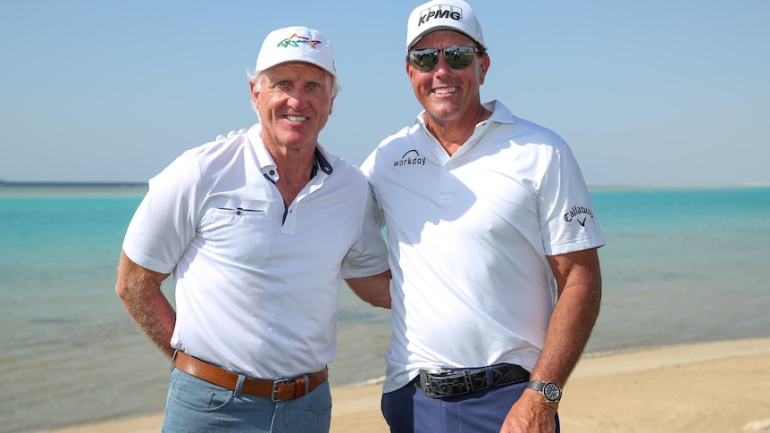 Greg Norman and Phil Mickelson smile together for a forward with the beach behind them