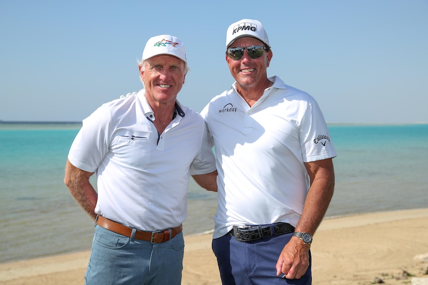 Greg Norman and Phil Mickelson smile together for a forward with the beach behind them